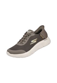 Zapatilla deportiva de malla gris con suela blanca, que presenta cordones, una punta redondeada y un logo en el lateral. El diseño es ligero y transpirable.