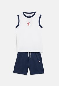 Λευκό αμάνικο τοπ με ναυτικό περίγραμμα και κόκκινο λογότυπο· συνδυασμένο με ναυτικό σορτς με ελαστική μέση και πλαϊνές τσέπες.
