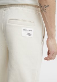 Beige sweatpants van katoen met een elastische tailleband, voorzien van een achterzak en een label met de tekst "11 PROJECT."