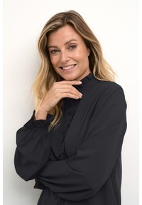 Black long-sleeve blouse with ruffled collar and cuffs, featuring a button-down front; smooth fabric texture and loose fit.