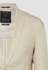 Blazer beige en mélange de lin avec col à revers cranté, poche poitrine et étiquette intérieure noire marquée "S.O PURE".