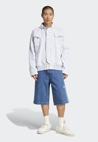 Heledsinine denim jakk kahe rinnataskuga, kombineeritud vabalt istuvate siniste lühikeste pükste ja valgete sneakersitega. Tekstuuriga kangas, päevane disain.