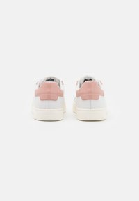Sneakers bianche con dettagli in pelle verniciata rosa, punta arrotondata, suola piatta bianca e logo sul tallone, caratterizzati da una texture liscia.