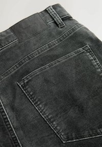 Mustat teksased  reljeefse pindalaga, tagaküljel on tasku ning linasest brändimärgistusega neljakandiline silt vöökoht.