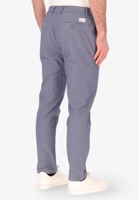 Chinos leggeri blu chiaro da uomo con finitura testurizzata, vestibilità slim, tasche posteriori e un piccolo etichetta del marchio vicino alla vita.