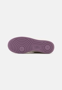 Sole tenisky Nike s kulatým vzorem pro stopy; fialový gumový materiál; hladký povrch; má na boku embosované logo Nike.