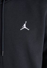 Mustern mustriga mustri pehmeast kangast, millel on rinnal valge Jumpman logo. Sisaldab reguleeritavat nööri.