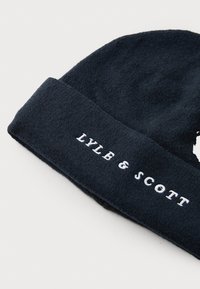 Bonnet marine en tissu doux, avec un revers replié et le texte brodé en blanc "LYLE & SCOTT" à l'avant.