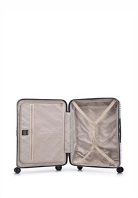 Hard shell suitcase with a black exterior, beige interior lining, zippered pocket, and cross straps for secure packing. Four wheels for mobility.