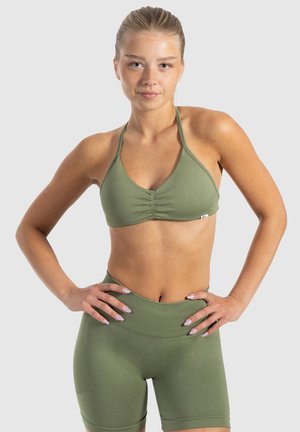Olijfgroene bikinitop met een geplooide voorkant, driehoekige cups en dunne bandjes. Bijpassende high-waisted shorts met ribbelstructuur en een nauwsluitende pasvorm.