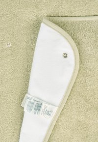 Light green towel with a textured surface and a white soft fold. Features a sewn edge, snap button, and a care label attached.