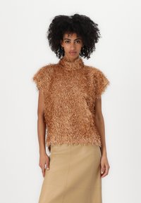 Metallisk kobberfuzzy strikkegenser med korte ermer og høy krage, b�året over et beige skjørt som har en myk, teksturert finish.