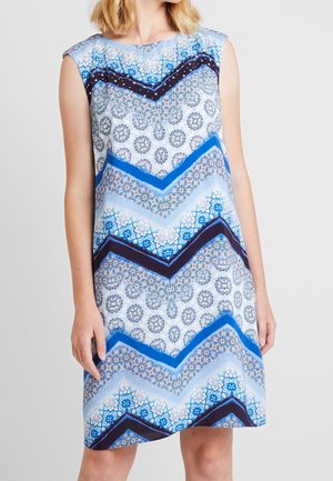 Modré a bílé šaty bez rukávů s geometrickými vzory, květinovými motivy a chevronovými akcenty v tmavě modrých a lila tónech.