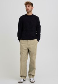 Mustade triipudega pikkade varrukatega top, beežid lahedalt istuvad püksid ja valged tossud mustade detailidega. Kujundatud mugavuseks ja igapäevaseks kandmiseks.