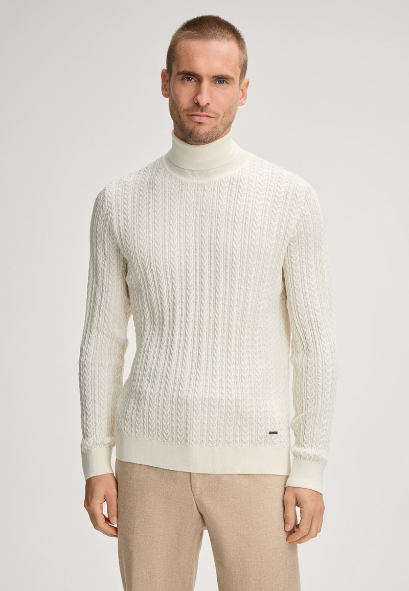 Crème kleurige coltrui met een textuur van kabelbreipatroon, voorzien van lange mouwen en geribbelde manchetten. Gemaakt met lichte bruine broek.