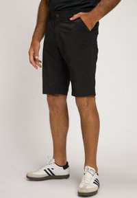 Sorte shorts med en glat overflade, der har en frontlukning med knap, sidelommer og et slim fit-design, stylet med hvide træningssko.