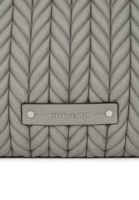 Sac à main en cuir gris avec une texture tressée, doté d'une étiquette métallique argentée affichant "KARL LAGERFELD" et des coutures renforcées.
