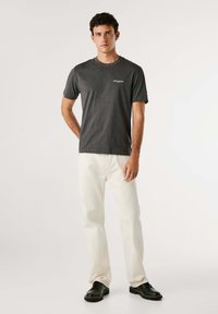 Grijze katoenen t-shirt met een ronde halslijn en korte mouwen, voorzien van een klein wit logo op de borst, gecombineerd met witte broeken.