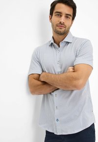 Korte mouwen overhemd met knopen in het wit met een blauw en grijs geometrisch patroon; heeft contrasterende knopen en een ontspannen pasvorm.