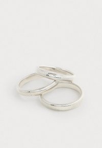 Sada troch strieborných prstencov tvarovaných ako pružiny, so hladkým povrchom a jednotným vzorom, s lesklým povrchom, ktorý zvýrazňuje ich dizajn.