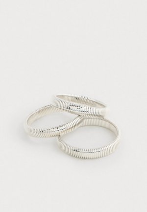 Conjunto de três anéis prateados em forma de espiral, com uma textura suave e padrão uniforme, apresentando um acabamento brilhante que destaca o seu design.