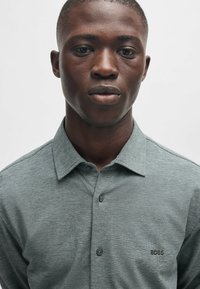 Korte mouwen, collared polo shirt in een gestructureerde grijze stof, met een klein geborduurd "BOSS" logo op de borst.