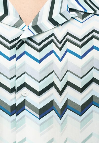 Κοντομάνικο πουκάμισο από ελαφρύ ύφασμα με σχέδιο ψαροκόκκαλο σε αποχρώσεις του μπλε, γκρι και μαύρου. Κλείσιμο με κουμπιά στον γιακά.