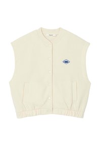 Veste sans manches crème avec un devant à boutons, un ourlet côtelé, des poches latérales et un patch en forme de diamant bleu sur la poitrine. Texture de tissu douce.