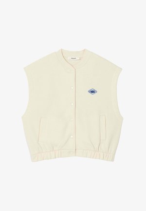 Veste sans manches crème avec un devant à boutons, un ourlet côtelé, des poches latérales et un patch en forme de diamant bleu sur la poitrine. Texture de tissu douce.