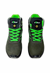 Scarpe di sicurezza nere e grigie con dettagli verdi. Le caratteristiche includono un colletto imbottito, suola in gomma resistente e protezione ESD.