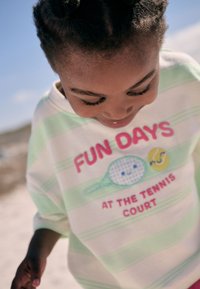 Light pastel striped sweatshirt featuring a playful tennis design with text "FUN DAYS AT THE TENNIS COURT" in vibrant colors.