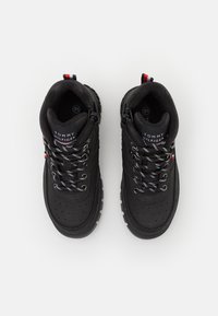 Czarne buty trekkingowe z gładką skórzaną cholewką, teksturowanymi sznurówkami i gumową podeszwą. Posiadają metkę z logo oraz wielokolorową pętelkę na pięcie.