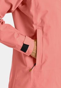 Pink waterproof jacket with a textured finish, featuring a cuff with a black Velcro closure and an external zippered pocket.