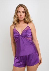 Ensemble de nuit en satin violet comprenant un top à bretelles fines orné de dentelle et un short assorti. Texture lisse, conception légère et coupe décontractée.