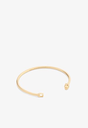 Bracciale a manica placcato in oro con un design aperto, estremità arrotondate con piccoli accenti verdi, superficie liscia e stile minimalista.