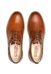 Zapatos de cuero marrón con cordones, acabado suave, puntera redonda, plantilla perforada, costuras en contraste y sutiles acentos rojos en los ojales.