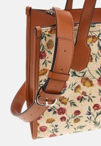 Borsa a tracolla in pelle marrone chiaro con motivo floreale intrecciato, dotata di una tracolla laterale, accessori in argento e cuciture dettagliate. Design strutturato e testurizzato.