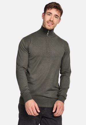 Pull-over vert olive avec col montant et fermeture éclair d'un quart. Texture côtelée, manches longues et coupe ajustée. Détails d'accent minimalistes.