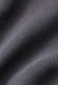 Tumši pelēks audums ar teksturētu, ribotu virsmu, kas izceļas ar smalkām viļņainām krokām, pievienojot dziļumu un vizuālu interesi.