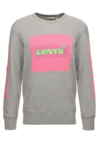 Sweatshirt gris à manches longues, arborant un grand motif en boîte rose avec "Levi's" en vert. Les accents incluent "CALIFORNIA" en rose sur la manche gauche.