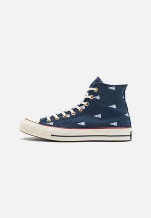 Sneaker alto navy in tela, con motivi triangolari bianchi, lacci bianchi a contrasto e suola di gomma con strisce rosse.