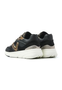 Schwarze und goldene Sneaker mit einer strukturierten Oberseite, Schnürverschluss, gepolstertem Kragen und einer dicken weißen Sohle mit einem gesprenkelten Fersenakzent.