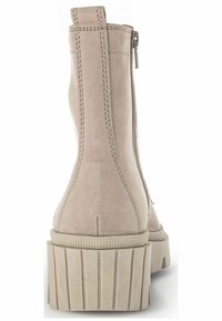 Beige suede ankle boots with a flared, textured platform sole and a side zipper. Features contrasting stitching along the seams.