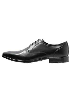 Chaussure habillée pour homme en cuir noir, bout pointu, fermeture à lacets et talon bas empilé, vue de profil sur fond blanc.