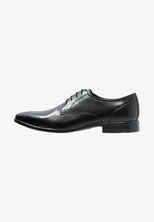 Chaussure habillée pour homme en cuir noir, bout pointu, fermeture à lacets et talon bas empilé, vue de profil sur fond blanc.