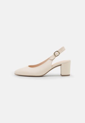 Zapato slingback de cuero beige con tacón de bloque y una hebilla dorada en la correa del tobillo, sobre un fondo blanco liso.
