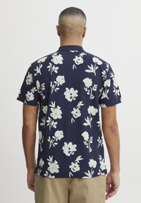 Marineblå kortermet skjorte med hvit blomsterdrift, med klassisk krage og myk tekstur. Tilpasset passform med buet kant.