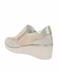 Scarpa slip-on color crema con tomaia perforata, dettaglio argentato nel tacco e suola a cuneo, realizzata con materiali lisci e testurizzati.