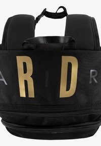 Rucsac negru cu litere aurii îndrăznețe, bretele laterale căptușite și un compartiment principal cu fermoar. Material texturat cu accente.