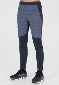Vadderade träningsbyxor i en kombination av ljusgrå och mörk marinblå material. Har en figurnära design, elastisk midja och sidofickor med dragkedja.